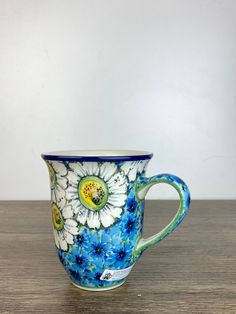 a blue and white flowered coffee cup sitting on top of a wooden table next to a wall