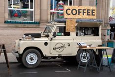 an old truck parked in front of a building with a coffee sign on it's roof