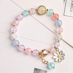 a close up of a bracelet on a table with a flower charm and other items