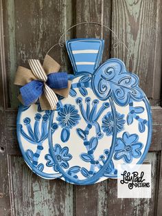 three blue and white plates hanging on a wooden door with a ribbon tied around the edge