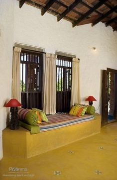 a bed sitting inside of a bedroom next to two windows