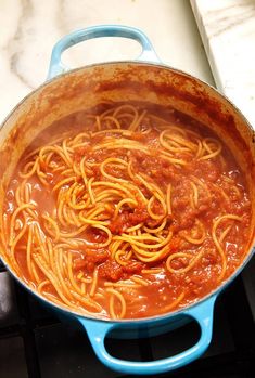 spaghetti being cooked in a pot on the stove