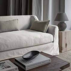 a living room with a white couch and two lamps on top of the coffee table