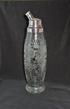 a glass vase with a metal lid on a black background