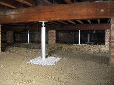 an unfinished room with exposed brick and white pipes in the floor, under which is concrete