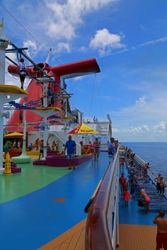 people are on the deck of a cruise ship looking out at the water and clouds