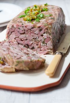 a piece of meat sitting on top of a white plate next to a knife and fork