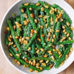 a white bowl filled with green beans and pine nuts