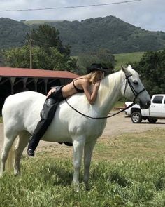 a woman sitting on top of a white horse