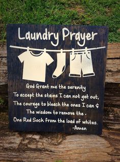 a wooden sign that says laundry prayer and clothes hanging on a line with green grass in the background