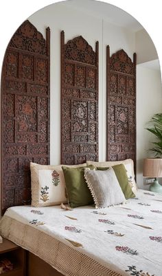 a bed with pillows and decorative wooden headboard