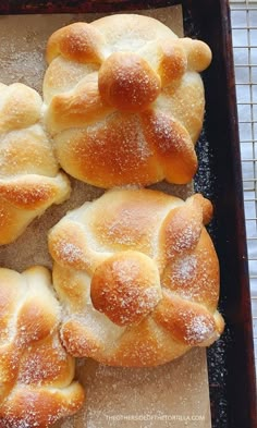 four hot cross buns on a baking sheet with powdered sugar sprinkles