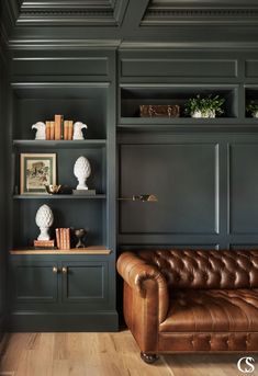 a brown leather couch sitting in front of a book shelf