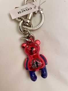 a red and blue teddy bear keychain with a name tag attached to it