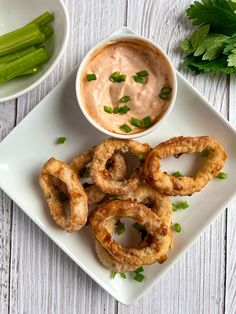 onion rings on a plate with dip and celery garnishes next to it