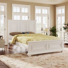 a white bed sitting on top of a wooden floor next to a dresser and mirror