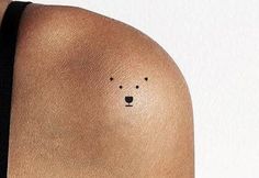 the back of a woman's shoulder with a small bear tattoo on her left arm