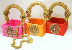 three different colored boxes with gold chains on the handles and one has a chain attached to it