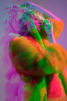 a woman in neon colored fur coat holding her hands to her face