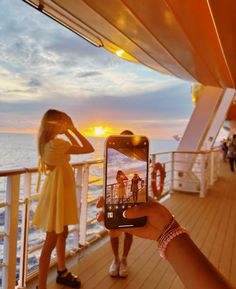 a woman taking a photo on her cell phone while standing on the deck of a cruise ship