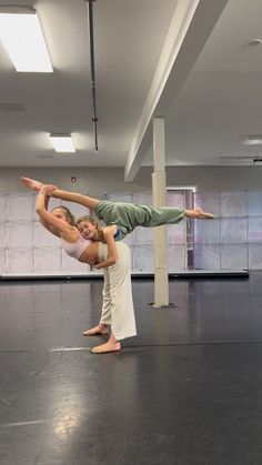 two people doing acrobatic tricks in an empty room with no one on the floor