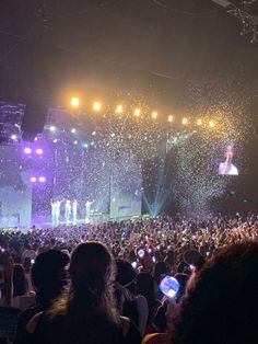 a large group of people at a concert with confetti thrown in the air