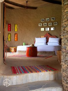 a bed sitting on top of a stone floor next to a wall filled with pictures