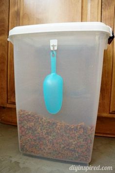 a plastic container filled with bird food and a blue scooper on the top of it