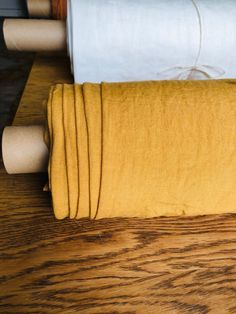 three rolls of yellow fabric sitting on top of a wooden table