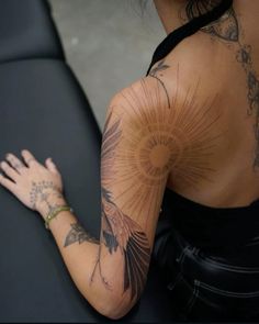 a woman with tattoos on her back and arm is sitting in front of a black chair