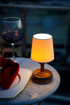 a table with a glass of wine and a napkin on it next to a candle