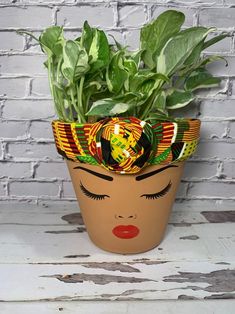 a potted plant with green leaves and a woman's face painted on it