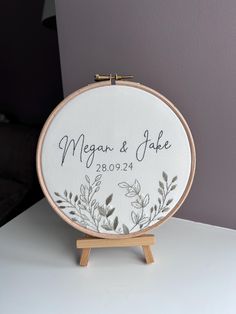 embroidered wedding guest sign on wooden easel with white background and greenery design in black ink