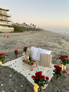 an outdoor seating area on the beach with roses and candles