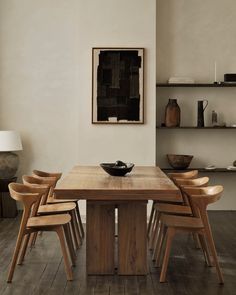 a dining room table with six chairs and a bowl on the top of it in front of shelves