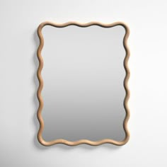 a mirror that is on the wall in front of a white wall with a wooden frame