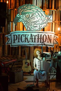 a woman playing an accordion in front of a sign that says pickathon on it