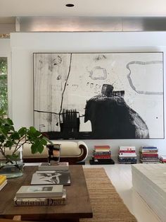 a living room filled with furniture and a large painting on the wall above it's coffee table