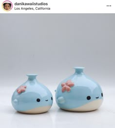 two blue ceramic vases with pink bows on the top one is shaped like a whale