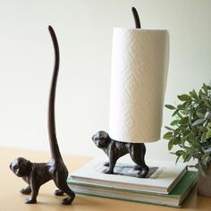 two monkey figurines are next to a toilet paper roll holder on a table