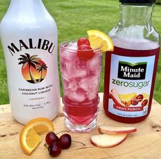 two bottles of lemonade, one with ice and the other with cherries are sitting on a wooden table