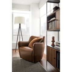 a brown leather chair sitting in front of a book shelf next to a lamp and bookshelf