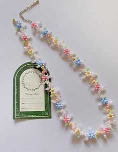 a necklace that has flowers on it and a tag attached to the beaded chain