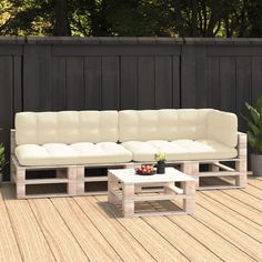 a couch sitting on top of a wooden floor next to a table and potted plant