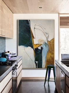 a painting hanging on the wall in a kitchen next to a stove and counter top