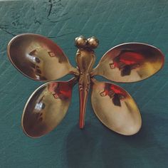 three spoons are arranged in the shape of a butterfly on a green surface with gold accents