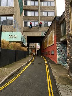 an alley with graffiti on the walls and yellow lines painted on the road in between two buildings