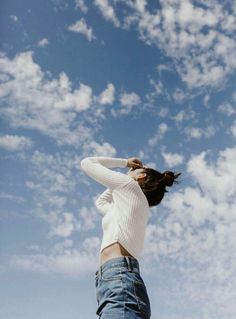 a woman is flying a kite high in the air with her hands behind her head