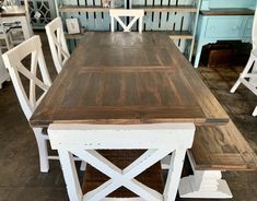 a dining room table with white chairs and wooden planks on the floor in front of it