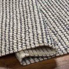 a close up view of a rug on the floor with wood and fabric in the background